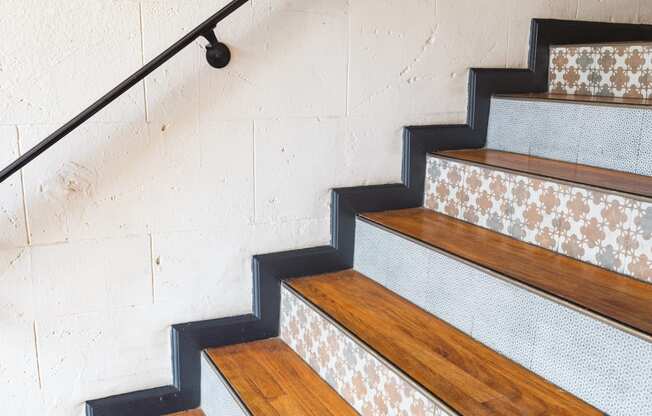 a staircase with wood treads and white tiles on the wall at Del Mor Apartments, Los Angeles, California