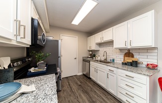 Kitchen with granite counters, modern cabinetry, & hardwood-style flooring