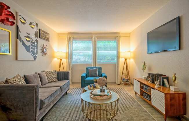 Living room in the Canvas Apartments in Nashville with midcentury modern decor, large couch, and double wide windows with blinds and curtains.