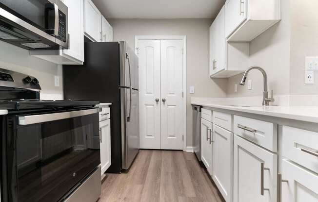 a kitchen with white cabinets and stainless steel appliances and a black refrigerator