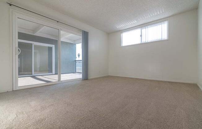 an empty room with a sliding glass door and a window at  Park Avenue Apartments, California,90815