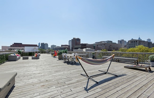 A hammock is on a wooden deck with a city skyline in the background.