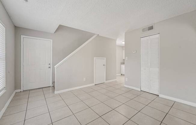 A spacious room with a white door and a tiled floor.
