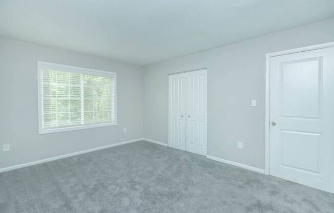 A room with a carpeted floor and two doors.