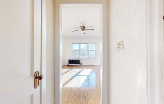 A Spacious Living Room with White Walls, Restored Hardwood Flooring, and a ceiling fan at The Park Apartments in Minneapolis, MN 55403