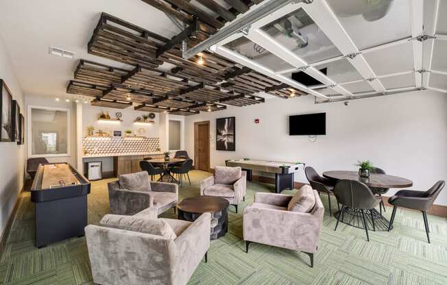 a lounge area with couches chairs and tables and a projection screen on the ceiling