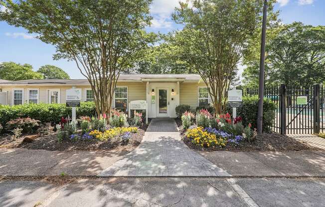 the entrance to a yellow house with a sidewalk and plants and trees