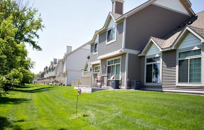 Exterior of Cascade Shores Townhome, the townhome has gray siding and white trim. Behind the townhome is a large lawn of lush green grass.