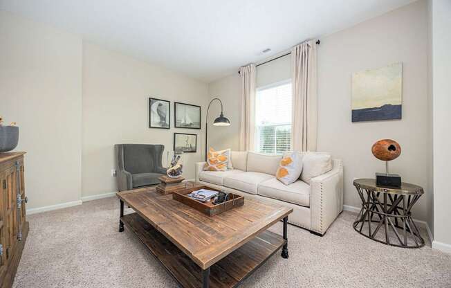 A living room with a white couch, a wooden coffee table, and a grey armchair.