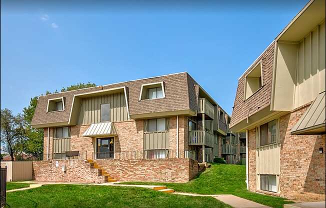 an apartment building with a grassy yard and a blue sky