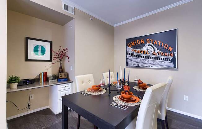 A dining room with a black table and white chairs.