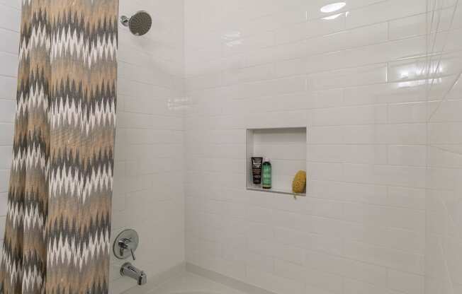 a bathroom with a white bathtub and a gray and white shower curtain