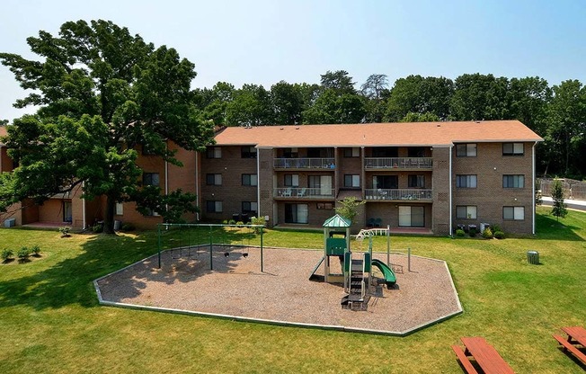 Far away view of apartment complex with playground at Gainsborough Court Apartments, Fairfax, VA