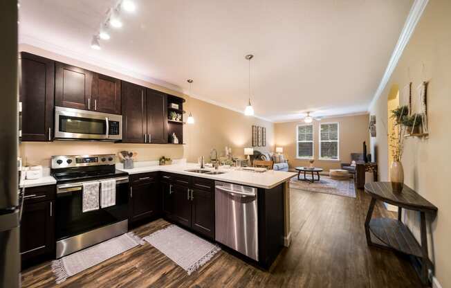 a kitchen and living room with dark wood cabinets and stainless steel appliances