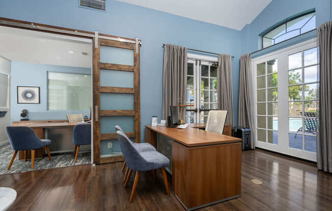 A room with a desk and chairs with a blue wall.
