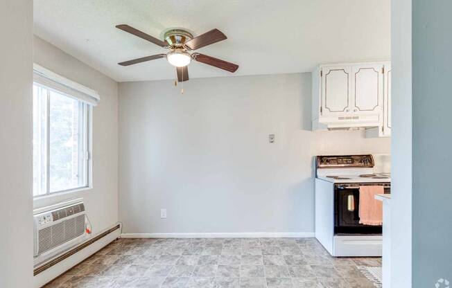 an empty kitchen with a ceiling fan and a window