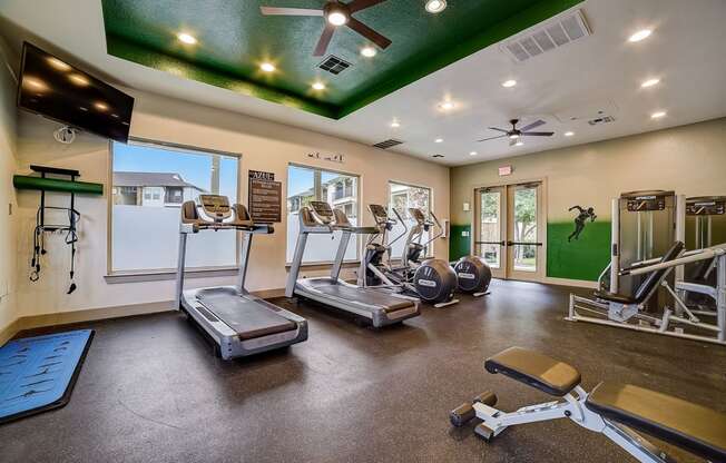 a gym with cardio equipment and a green ceiling