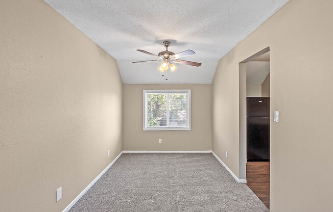 an empty room with a ceiling fan and a window