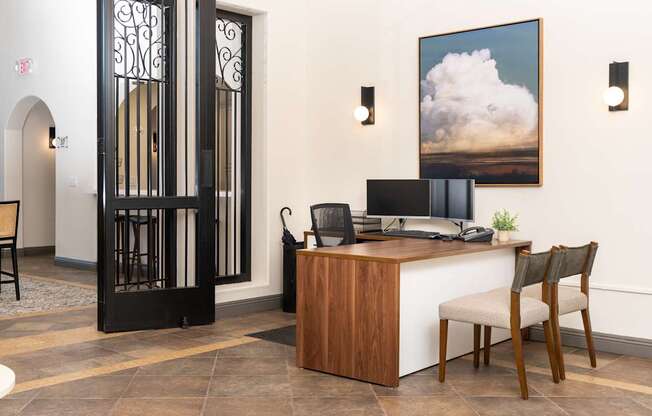 A room with a desk and a chair in front of a painting.