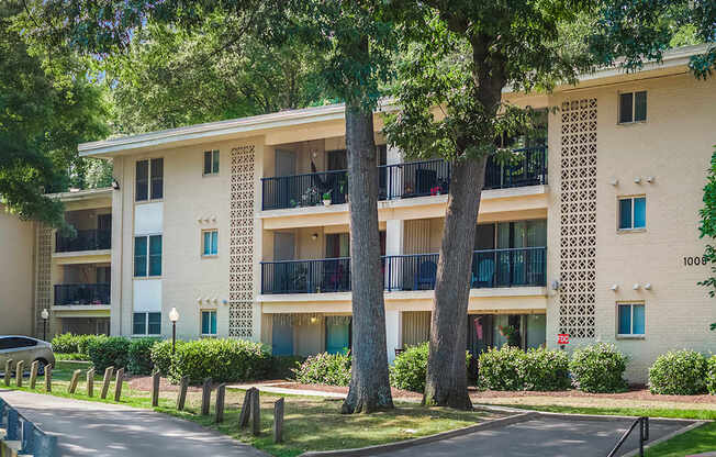 A white apartment building with balconies and trees in front.