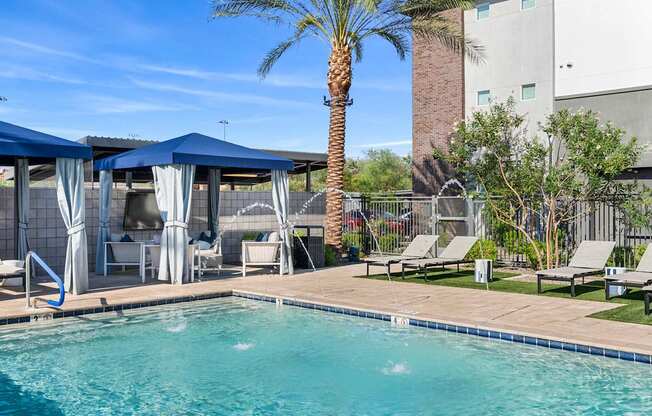 A pool area with a palm tree and sun loungers.