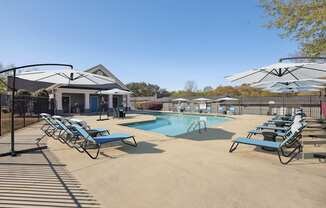 A pool area with sun loungers and a building in the background.