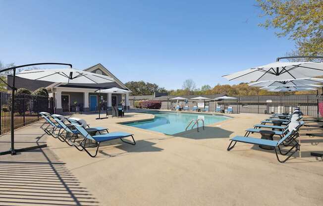 A pool area with sun loungers and a building in the background.