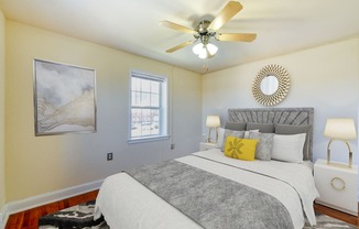 Bedroom with bed, nightstands, large windows, and ceiling fan  at hillside terrace apartments in washington dc
