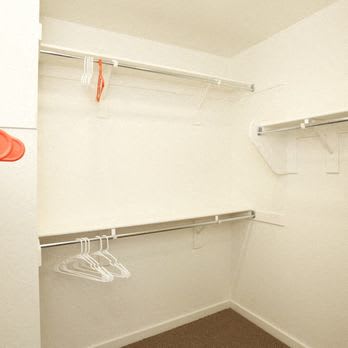 a white closet with shoes and hangers in it
