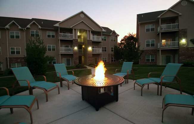 round gas firepit surrounded by blue lounge chairs