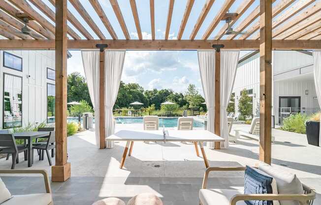 A wooden pergola over a patio with a table and chairs.