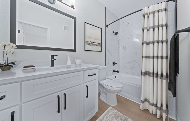 a bathroom with white cabinetry and a shower and a toilet