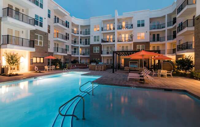 a swimming pool in front of an apartment building at night