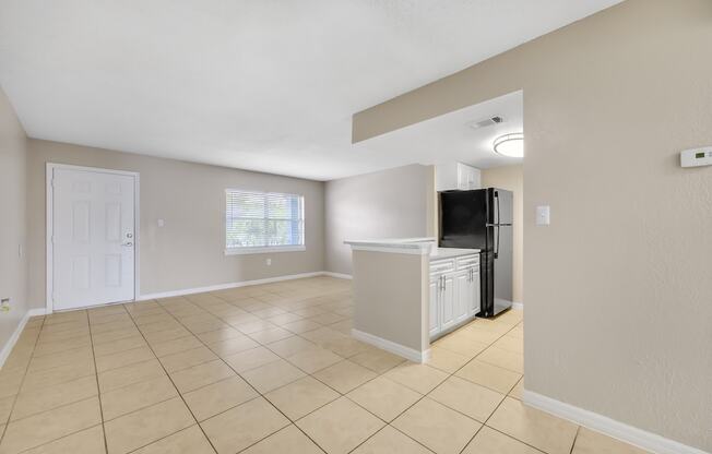 the spacious living room and kitchen of a home with a tiled floor