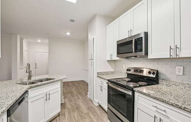 A renovated kitchen with white cabinets, granite countertops through out and stainless steel appliances