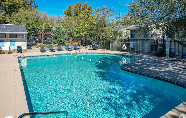 A swimming pool surrounded by trees and a fence.