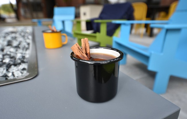 A black mug with cinnamon sticks on a grey table.