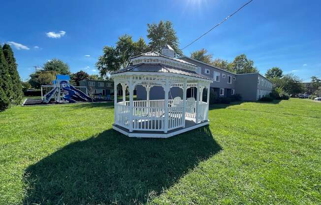 a white gazebo in the middle of a yard with a playground
