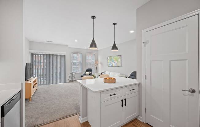 an open kitchen and living room with white cabinets and a white counter top