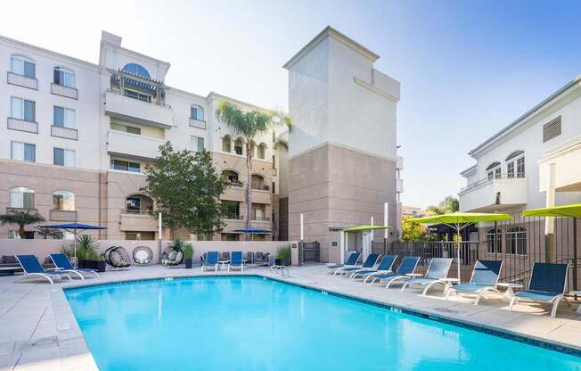 A pool surrounded by lounge chairs in front of a building. at La Jolla Crossroads Apartments, San Diego, CA, 92122