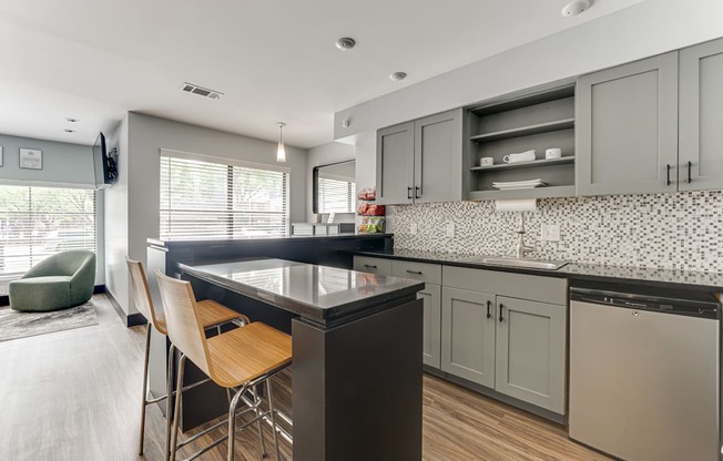 A kitchen with a black countertop and wooden chairs.
