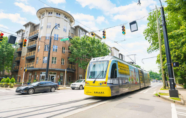 a yellow streetcar on a city street in front of a building