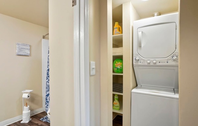 A white dishwasher is built into a wall next to a toilet paper roll.