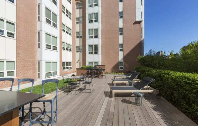 a large patio with tables and chairs in front of an apartment building at Amelia, Quincy, Massachusetts