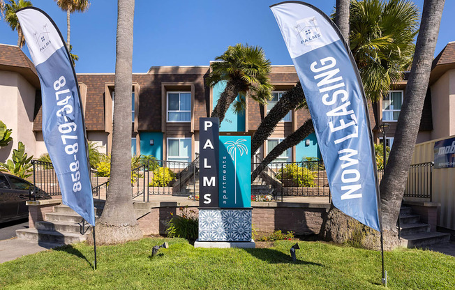 A leasing sign is in front of a building with palm trees.