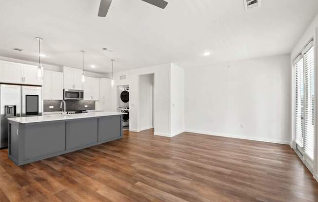 an open kitchen and living room with a wood floor and white walls
