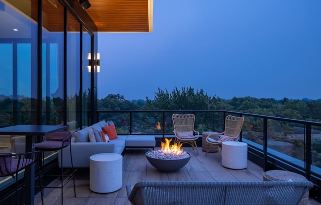 a patio with a fire pit and chairs on a balcony