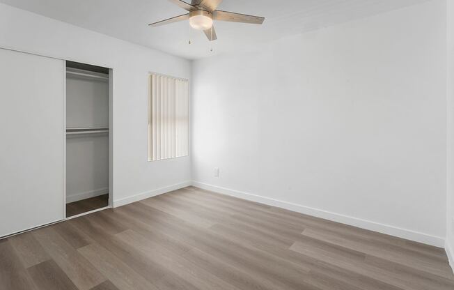 A room with a ceiling fan and wooden flooring.