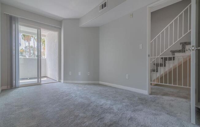 an empty living room with a sliding glass door and a staircase  at Warner Center Townhomes, Canoga Park, CA 91303