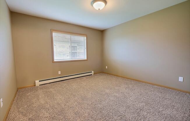 a bedroom with carpet and a window. Fargo, ND Urban Plains Apartments